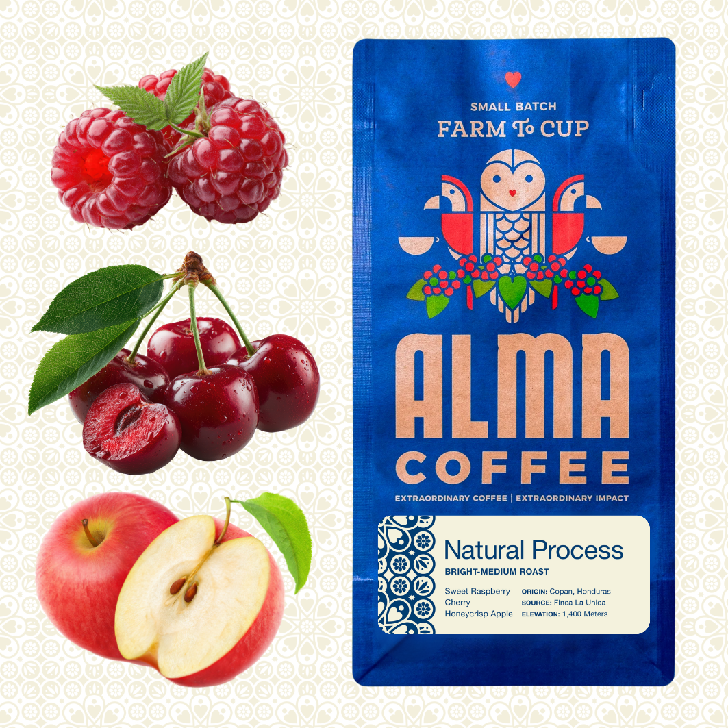 Alma Coffee small batch farm to cup coffee package in blue with raspberry, cherry, and apple illustrations, shown beside fresh raspberries, cherries, and an apple on a light patterned background.