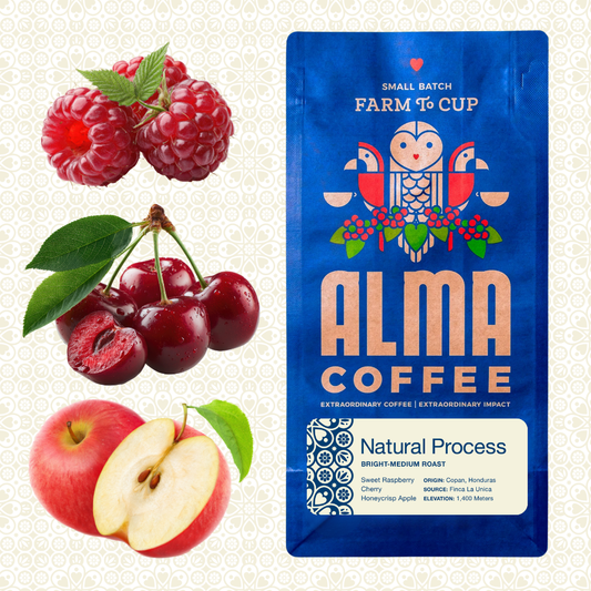 Alma Coffee small batch farm to cup coffee package in blue with raspberry, cherry, and apple illustrations, shown beside fresh raspberries, cherries, and an apple on a light patterned background.